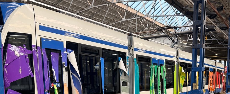 Detail van losse grafische foliebanen tijdens montage op tramdeuren
