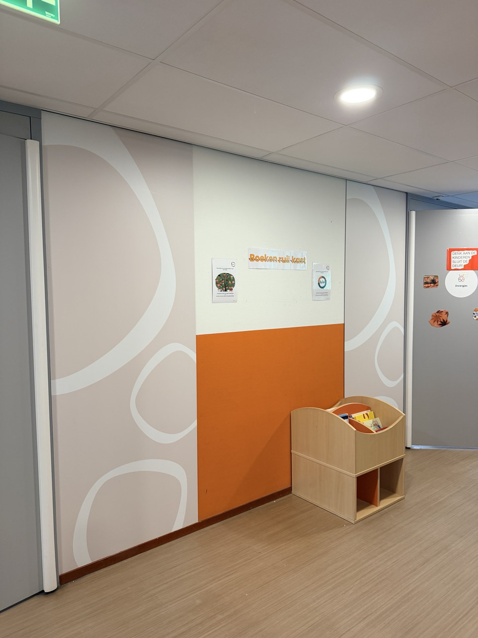 Decoratieve wandfolie naast een boekenruilkast in een kinderomgeving