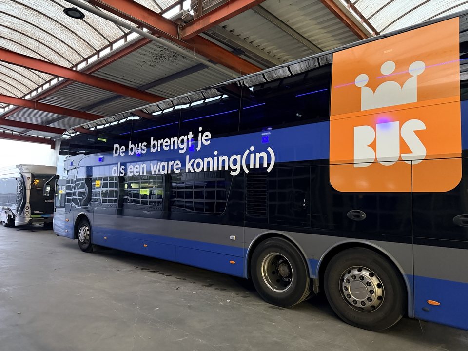 Bus met een aangebrachte grafische huisstijl in een werkhal