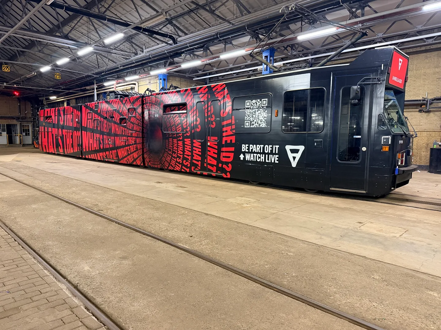 Museumtram met rood-zwarte ADE-bestickering in de remise