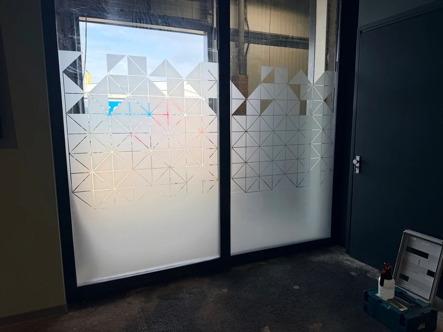 Twee ramen met decoratieve raamfolie met geometrisch patroon en matte vlakken.
