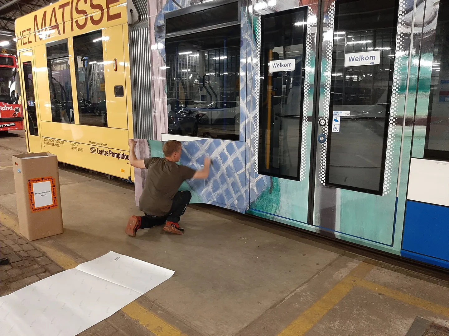 PIT brengt kleurrijke folie aan op een GVB-tram in de remise in Amsterdam